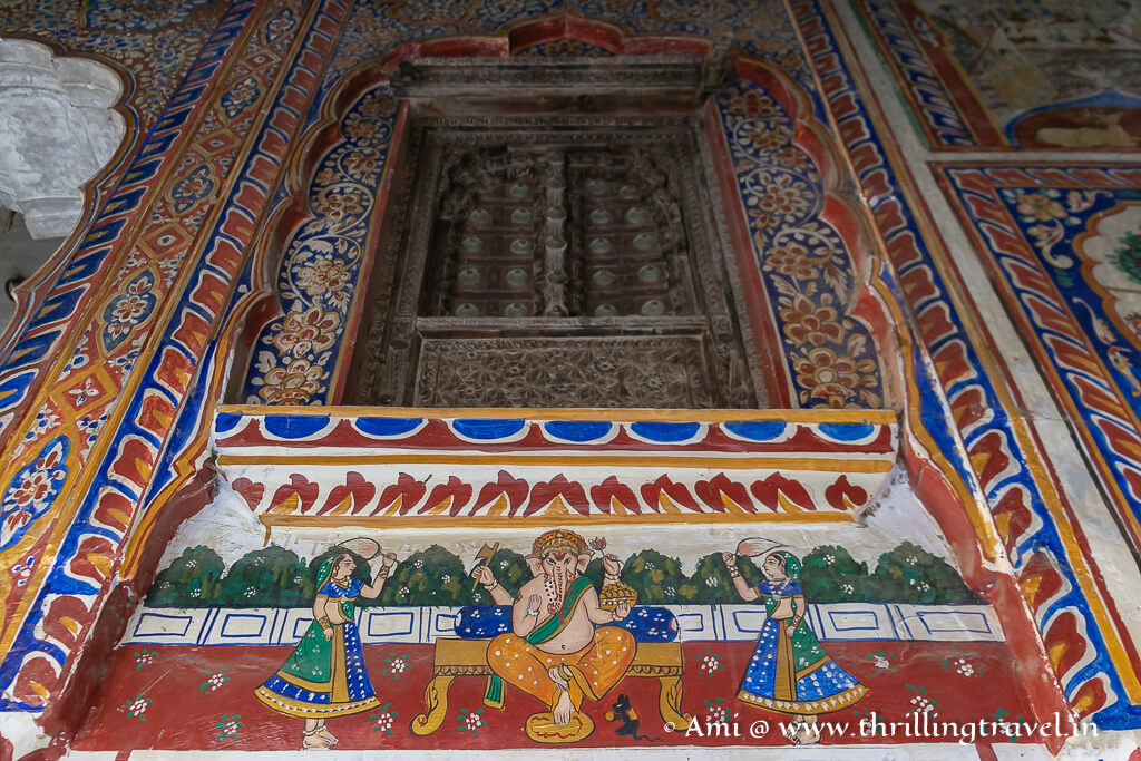 The jharokha windows framed by the frescoes past the main entrance of the Goenka Double Haveli