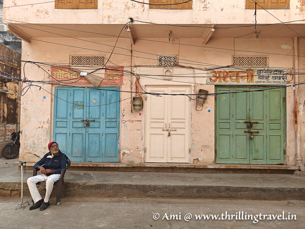 Colorful doors in UNESCO World heritage city of Jaipur with a local dressed in traditional clothes sitting outside